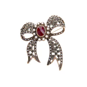 Detailed view of antique hollow bow brooch with red gemstone, pearls and crystals