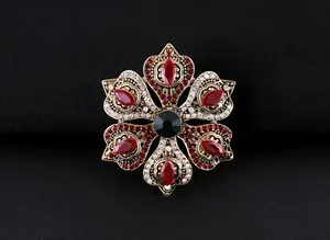 Detalle de un broche de lujo barroco vintage con piedras preciosas rojas y verdes sobre negro