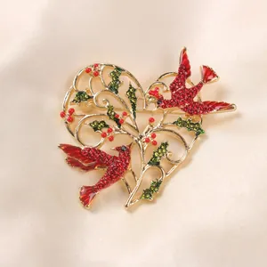 Close-up view of vintage heart-shaped brooch with red birds and holly leaves on satin