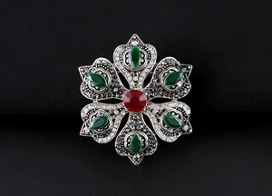 Vista detallada del broche barroco con piedras marquesa verdes y cristal rojo central