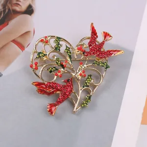 Detailed view of a vintage heart-shaped brooch with red enamel birds and rhinestones