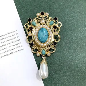Detailweergave van een vintage barokke broche met turkoois en een druppelparel