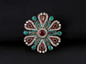 Vista detallada de un lujoso broche barroco vintage con brillantes rojos y verdes.