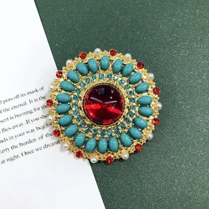 Detailopname van een vintage broche in barokstijl met rode en turquoise stenen
