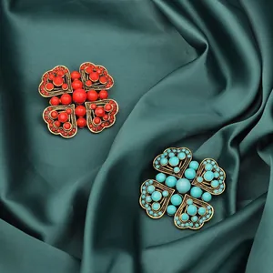 Detail of vintage red and turquoise blue heart brooches on green silk fabric