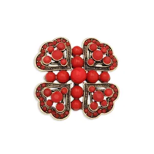 Detailed view of a vintage red bead brooch with intricate metallic heart patterns