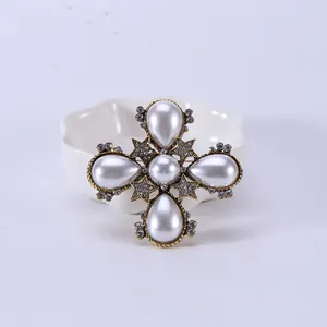 Detailopname van een luxe barokke kruisspeld met druppelvormige parels en strass.