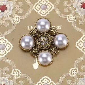 Gedetailleerde macro-weergave van een barokke vintage kruisbroche met parels en goud metaal
