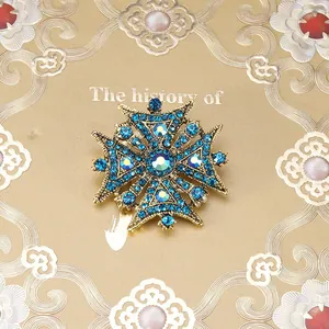 Macrodetail van een barokke vintage gouden kruisbroche met blauwe strassteentjes