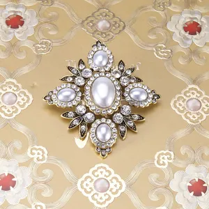 Detail van een barokke vintage kruisbroche met witte parels en glanzende strass-steentjes
