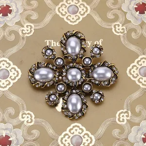 Gedetailleerd overzicht van barokke vintage kruisbroche met parels en strassteen