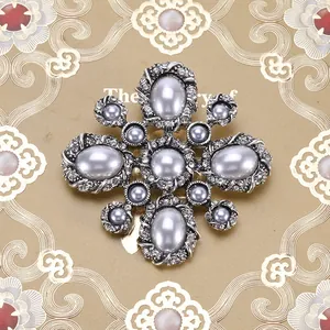 Gedetailleerde macro-opname van een vintage barokke kruisbroche met grijze parels en strass