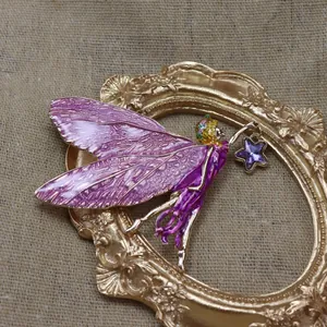 Détail d'une broche fée vintage en émail violet avec un cadre doré ornementé.