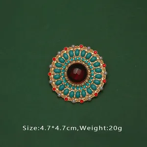 Vue détaillée d'une broche baroque vintage avec pierre rouge centrale et perles