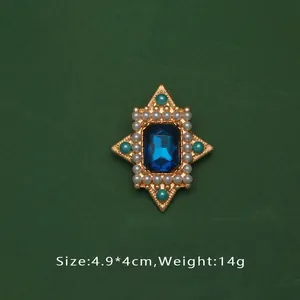 Gros plan d'une broche de style baroque avec pierre bleue, perles et finition dorée.