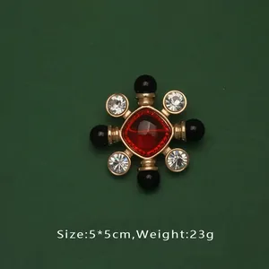 Gros plan d'une élégante broche baroque avec une pierre rouge et des perles noires