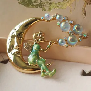 Détail macro d'une broche vintage lune dorée et fée verte avec des bulles irisées