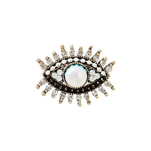 Vintage Evil Eye-speld met centrale parel en strass-steentjes op een witte achtergrond