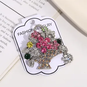 Close-up detail of a vintage flower basket brooch with colorful rhinestones on white card