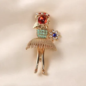 Close-up detail of an elegant gold ballerina brooch with a red bead and rhinestones