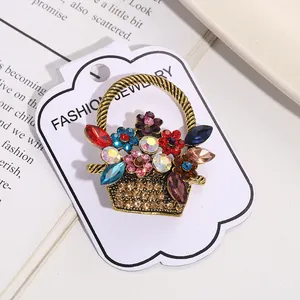 Close-up of a vintage flower basket brooch featuring colorful rhinestones on a card.