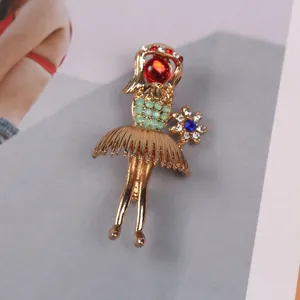 Close-up detail of elegant gold-toned girl brooch featuring red gem and tiny rhinestones