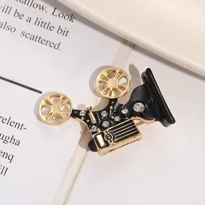 Close-up of a vintage movie projector brooch with black enamel finish and shiny rhinestones