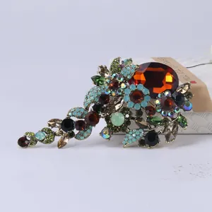 Gedetailleerde close-up van een vintage bloemenbroche met amber en turkoois kristallen
