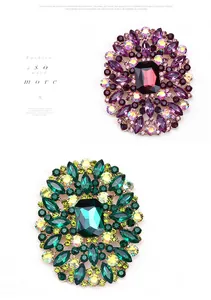 Detailed macro view of two vintage crystal brooches in purple and green emerald tones