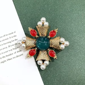 Macrodetail van een vintage barokke gouden broche met groene steen en parels