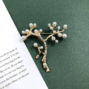 Elegante vintage gouden boomtak broche met witte parels op groene achtergrond