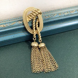 Detailweergave van matgouden vintage barokke broche met hangende kettingkwastjes