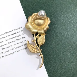 Gedetailleerd beeld van een vintage barokke roosspeld in mat goud met parel accent