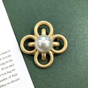 Detailopname van een vintage barokke broche met matgouden afwerking en een grote parel.