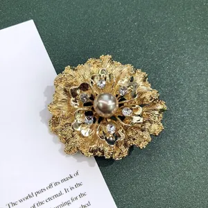 Detailopname van een vintage barokke bloemenbroche in mat goud met een parelcentrum