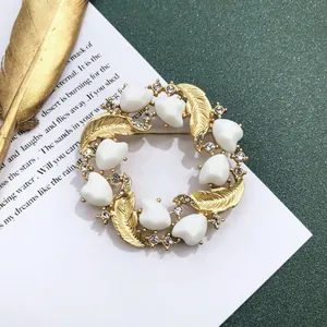 Detail van vintage barokke gouden kransbroche met witte hartstenen en schitterende kristallen