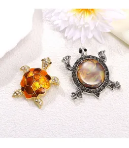 Détail de deux magnifiques broches tortues vintage avec émail et nacre irisée.