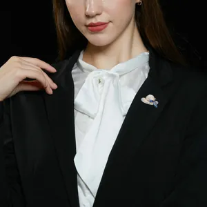 Detailansicht einer eleganten Hut-Brosche mit blauem Band auf einem Blazer