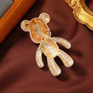 Macro-weergave van achterkant gouden teddybeer broche met metaaltextuur en speldsluiting
