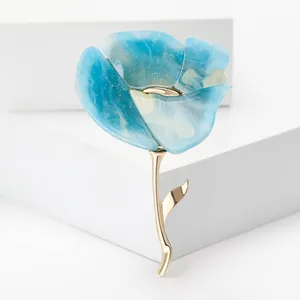 Gros plan d'une broche fleur en résine bleue avec tige en alliage doré et pétales pailletés