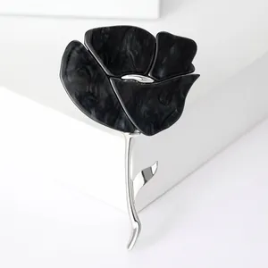 Broche fleur élégante avec pétales effet marbre noir et tige en argent poli.