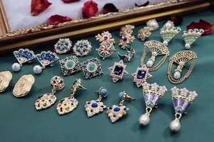 Collectie barokke vintage oorbellen met kleurrijke strass-steentjes en parels op groen vlak.