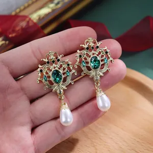 Detail van barokke vintage oorbellen met groene strassteentjes en parelhangers