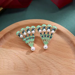 Detailweergave van barokke waaieroorbellen met groen emaille en ingelegde witte parels.