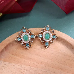 Detailopname van vintage barokke oorbellen met groene stenen, parels en kristallen.
