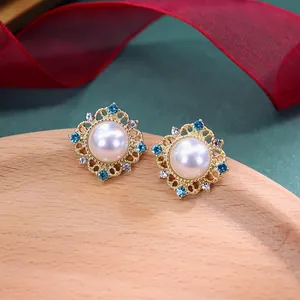 Macroweergave van vintage barokke gouden oorbellen met parel en blauwe strass steentjes.