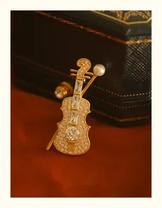 Macro view of gold violin brooch with intricate rhinestone inlay and pearl detail