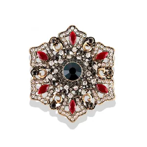 Détail d'une broche baroque vintage avec cristaux rouges et finition dorée antique.