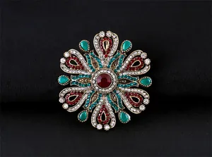 Vue détaillée d'une broche baroque en cristal avec pierres rouges et vertes sur fond noir