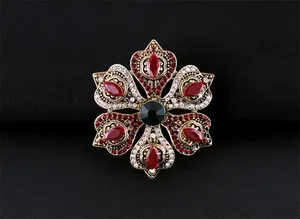 Détail macro d'une broche baroque vintage avec cristaux rouges et verts sur fond noir texturé